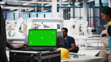 Siyah adam, güneş paneli imalat fabrikasındaki kroma anahtar ekranı vasıtasıyla robotik makine ayarlarını ayarlıyor, vites performans sorunlarını teşhis ediyor. Fotovoltaik fabrikası uzmanı. Kamera B.