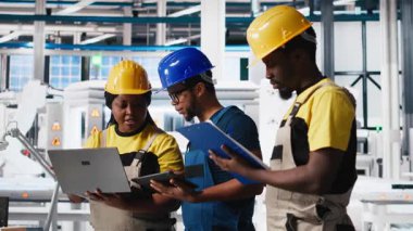 Güneş panelleri fabrikasında çalışan bir grup siyah işçi cihaz ve belgelerdeki verileri inceliyor. Fotovoltaik tesisi mühendisleri yenilikçi güneş hücreleri dizayn prototipi üzerinde çalışıyorlar. Kamera A.