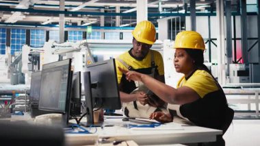 Afrika kökenli Amerikalı işçiler güneş paneli fabrikasındaki imalat ekipmanlarını kontrol ediyor, belge dosyalarını okuyor. Endüstriyel tesisteki mühendisler üretim sürecini inceliyor. Kamera B.