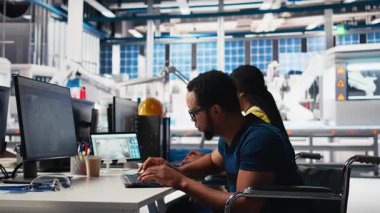 Güneş panelleri üretmek için CAD yazılımını test eden Afro-Amerikan tekerlekli sandalye kullanıcısı, güneş enerjisi endüstrisinde çalışan fabrika mühendisi. İşinde engelli bir uzman. Kamera B.