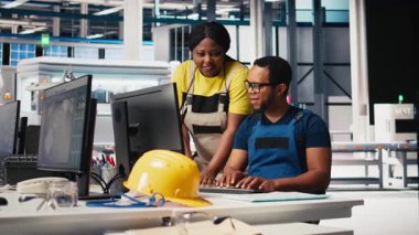 Fotovoltaik fabrikasındaki teknisyenler güneş panelleri montaj hatlarını inceliyor, sanayi yönergelerini okuyor ve sorunsuz üretim sağlıyorlar. Siyah takım güneş pili aktivitesini optimize ediyor. Kamera B.