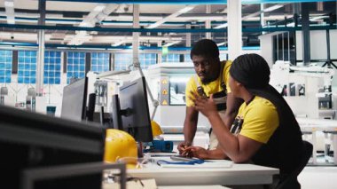 Yüksek teknolojili bir güneş paneli fabrikasında çalışan siyah mühendislik ekibi, dinlenme süresini ve kusursuz üretim sürecini azaltıyor. Teknisyenler güneş enerjisi üretimini optimize ediyorlar. Kamera B.