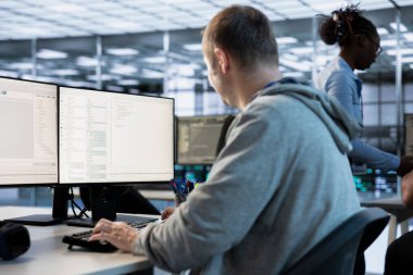 Bilgisayar mühendisi bilgisayar ekranına bakıyor, ağ güvenlik veri merkezinde çalışıyor, en iyi performansı sağlıyor. Sunucu merkezini denetleyen, enerji tüketimini izleyen bir adam.