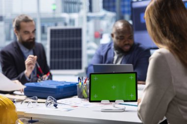 Endüstriyel fabrikadaki işadamları model cihazı üzerinde araştırma yapıyorlar. Yatırımcılar ve fabrika yönetimi, tecrit edilmiş ekran tableti kullanarak ekipman üretim genişlemesi stratejilerini analiz ediyor