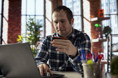 İnternet alışverişi yapan, dizüstü bilgisayarda kredi kartı bilgilerini yazan, eşyaları el arabasına yerleştiren, çıkış adımlarına ilerleyen bir adam. Çevrimiçi işlem yapan kişi, web sitesine ödeme yöntemi ekliyor