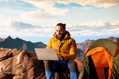 İşkolik kâşif her zaman kesintisiz işlere bağlanır ve bağımlıdır. Dağın tepesinde dizüstü bilgisayarını açar. İnternet bağımlılığına sahip genç gezgin güçlü bir sinyalin keyfini çıkarıyor.
