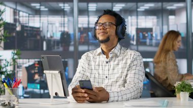 Afrika kökenli Amerikalı genel müdür tahminleri değerlendirirken kulaklıkla müzik dinliyor, masasında kendini rahat ve çoklu görev başında hissediyor. Veri analisti hedeflere, strateji planlamasına odaklanıyor. Kamera A.