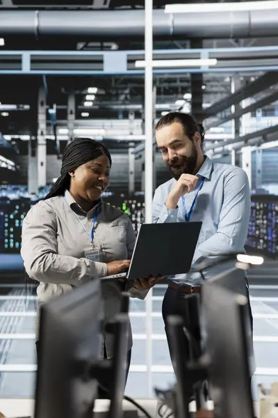 Sunucu çiftliğinde dizüstü bilgisayar kullanan neşeli mühendisler, verileri analiz ediyorlar. Not defteri, sistem bütünlüğü ve güvenliği sağlayarak veri merkezindeki altyapıyı inceleyen neşeli ekip çalışanları