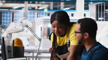 Afrika kökenli Amerikalı meslektaşlar güneş enerjisi üretim hattındaki güç verilerini analiz ediyor, takım çalışması masaüstü bilgisayarının etrafında toplandı. Mühendisler sürdürülebilir enerji için yapılandırmaları optimize ediyorlar. Kamera A.