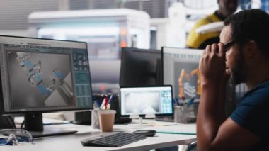 Güneş paneli fabrikasında çalışan Afro-Amerikan tekerlekli sandalye kullanıcısı yenilenebilir enerji sistemlerini optimize ediyor. Mühendis, engelli dostu bir enerji santralinde robot silah otomasyonunu inceliyor. Kamera A.