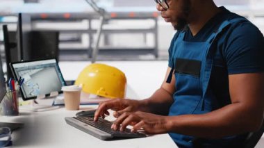 Afrika kökenli Amerikalı mühendis, bir güneş paneli imalat fabrikasında çalışarak, masaüstündeki güneş enerjisi makinelerinden veri topluyor. Otomatik yenilenebilir enerji üretim hattında erkek teknisyen. Kamera A.