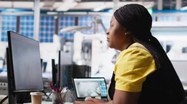 Afrika kökenli Amerikalı uzman güneş enerjisi santralindeki fotovoltaik sistemleri tasarım için bir PC yazılımı üzerinde çalışıyor. Mühendis yenilenebilir enerji operasyonlarındaki yapılandırmaları inceliyor. Kamera A.