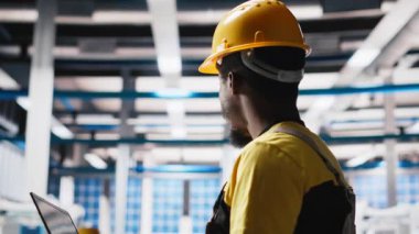 Güneş paneli fabrika üretim hatlarını izlemek için dizüstü bilgisayar kullanan bir mühendis sorunlu fotovoltaik ekipmanlarla sorunsuz üretim akışını sağlıyor. Alternatif enerji için otomasyon. Kamera A.