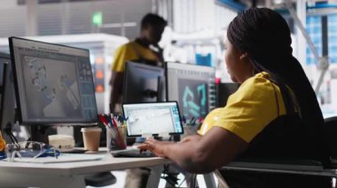 Fotovoltaik fabrikası mühendisi tekerlekli sandalye kullanıcısı endüstriyel bir yazılımda güneş panellerini geliştiriyor, imalat endüstrisinde bilgisayar üzerinde çalışıyor. Yenilenebilir enerji. Kamera A