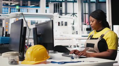 Güneş paneli fabrikasında bilgisayar verileri üreten teknisyen gözlemcileri, verimli güneş enerjisi üretimini desteklemek için çalışan ince unes ekipman ayarları. Kadın montaj hattının yanında oturuyordu. Kamera A.