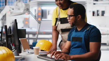 Fotovoltaik fabrikasındaki teknisyenler güneş panelleri montaj hatlarını inceliyor, sanayi yönergelerini okuyor ve sorunsuz üretim sağlıyorlar. Siyah takım güneş pili aktivitesini optimize ediyor. Kamera A.