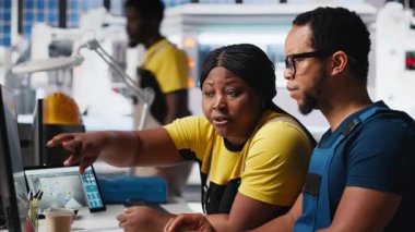 Çalışanlar, temiz enerji santralindeki fotovoltaik tasarım güncellemeleri üzerinde çalışarak, güneş paneli fabrikasındaki operasyonel verimliliği azaltmaya çalışıyorlar. Siyahi mühendisler teknik sorunları hallediyor. Kamera A.