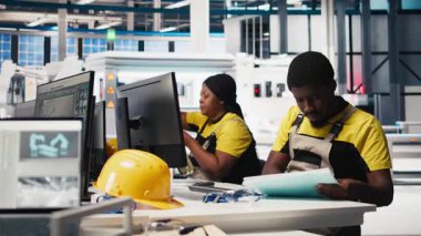 Afrika kökenli Amerikalı denetçi ofisteki enerji kontrol sistemlerini inceliyor, güneş enerjisi üretim teknolojisiyle çevrili. Erkek mühendis güneş enerjisi ve üretimi dengeler. Kamera B.