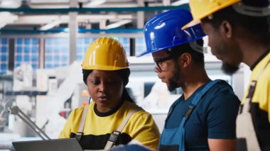 Güneş paneli fabrikasındaki mühendislik grubu tablet aracılığıyla makine ayarlarını ayarlıyor, verimli üretim için üretim ve yapılandırmayı denetliyor. Takım çalışması. Kamera A.