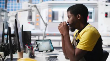 Afrikalı Amerikalı teknisyen, gelişmiş izleme ve üretim araçları kullanarak PC istasyonundaki yenilenebilir enerji ölçümlerini değerlendiriyor. Mühendis güneş enerjisinin hassasiyetini geliştiriyor. Kamera A.