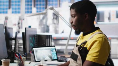 PC tabanlı güneş teknisyeni üretim fabrikasındaki otomasyon verilerini inceledi, üretim endüstrisi yenilenebilir enerjiye odaklandı. İşçi güneş panellerini ve makine performansını izliyor. Kamera A.