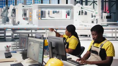 Siyah çalışan, güneş paneli konfigürasyonunu masaüstü araçları, fabrika üretimini optimize etme ve sorun giderme yoluyla yönetiyor. Teknisyen enerji sistemi parametrelerini bilgisayarda güncelliyor. Kamera B.