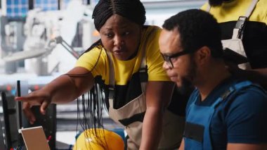 Fabrika işçilerinden oluşan siyah ekip, endüstriyel fabrikadaki güneş panelleri üretim hattında birlikte çalışarak teknik sorunları veya hataları düzeltiyorlar. Yenilenebilir enerji. Kamera A.