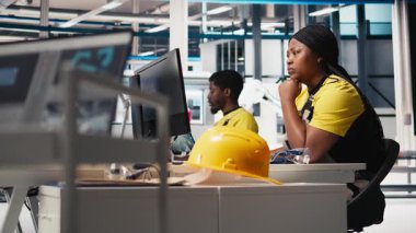 Güneş paneli mühendisi, elektrik santralindeki yüksek teknoloji üretim ekipmanlarını kullanarak, sistem tasarımlarını masaüstü bilgisayarında gözden geçiriyor. Teknisyen fotovoltaik teknolojiyi optimize etmeye çalışıyor. Kamera B.