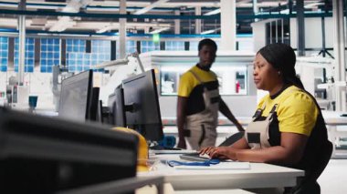 Siyah teknisyenlerden oluşan bir ekip fabrikada üretilen güneş panellerini inceliyor ve üretim hattı için kalite kontrolü yapıyor. Yenilenebilir enerji endüstrisi üzerinde çalışan mühendisler. Kamera B.