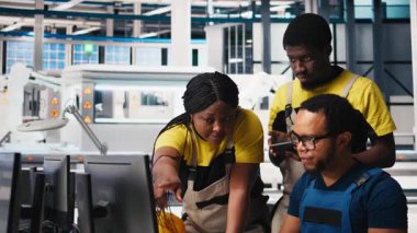 Fabrika işçilerinden oluşan siyah ekip, endüstriyel fabrikadaki güneş panelleri üretim hattında birlikte çalışarak teknik sorunları veya hataları düzeltiyorlar. Yenilenebilir enerji. Kamera B.