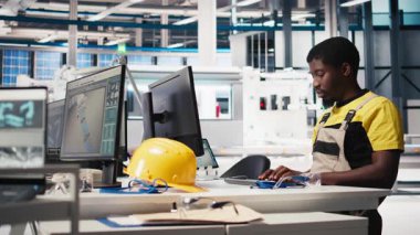 Güneş pili fabrikasında robotik montaj hattını programlayan siyah işçiler, yüksek teknoloji yazılımlarıyla otomasyon için çalışıyorlar. Erkek mühendis fotovoltaik sistemi ve makineleri test ediyor. Kamera B.