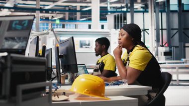 Afrika kökenli Amerikalı mühendis güneş enerjisi fabrikasındaki enerji tüketim yazılımlarını analiz ediyor, güneş pili üretimini arttırmak ve otomatik makine sistemlerindeki hataları azaltmak için PC programını kullanıyor. Kamera B.