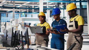 Fotovoltaik fabrikasındaki tüm siyah müfettişler belgeleri inceleyip, güneş panellerini montaj hattına yerleştiren robotların performanslarını inceleyecekler. Güneş pilleri tesisini denetleyen denetçiler. Kamera B.