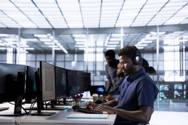 Veri merkezindeki adam kulaklıkla şarkılar dinlerken programlama dillerini uygulamalar oluşturmak için kullanıyor. Sunucu merkezi yazılım geliştiricisi müzik dinliyor, hata ayıklama kodu