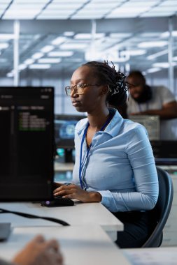 Veri merkezinde ağ yönetim becerilerini kullanarak bilişim altyapısını yöneten ve optimize eden sistem yöneticisiyim. Afro-amerikan sunucu odası çalışanı ekipmanları güncelliyor, işletme maliyetlerini düşürüyor