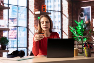 Bilgisayarındaki şeyleri ödeyen beyaz bir yetişkin kredi kartı numaralarını girerek işlemi onaylıyor ve siparişi veriyor. İnternetten alışveriş yapıyor..