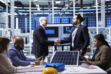 Endüstriyel fabrika hissedarları el sıkışarak yatırım fırsatları üzerine araştırma yapıyorlar. Fabrika hissedarları el sıkışıyor, birbirlerini selamlıyor, rakip analizler yapıyorlar.