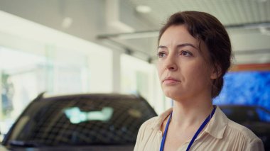 Ne tür bir araca yatırım yapacaklarını seçerken bireylerin karar almalarına yardımcı olmak için tutulan neşeli araba galerisi yöneticisinin portresi. Neşeli satıcı kadın müşterilere yardım etmeye hazır, kapatın.