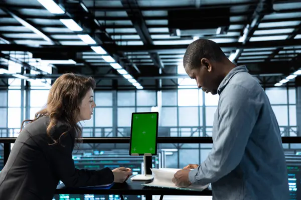 Sunucu odasını model cihazıyla denetleyen bir kadın. Belge evraklarını okuyan, sorun çıkaran bir donanım. Sunucu merkezinde teftiş yapan denetleyici, yeşil ekran tableti hakkındaki teknik dosyaları okuyor