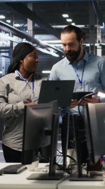 Sunucu odasında gülümseyen bir mühendislik ekibi altyapı tanılarını inceliyor. Veri merkezinde sistem bütünlüğünü korumak için performans verilerini analiz eden bilişim uzmanları ve