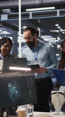 Sunucu odasında gülümseyen bir mühendislik ekibi altyapı tanılarını inceliyor. Veri merkezinde sistem bütünlüğünü korumak için performans verilerini analiz eden bilişim uzmanları ve