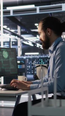 Sunucu odasındaki dikey video mühendisi monitördeki ani fidye virüsü tespitine yanıt veriyor. Kritik verileri korumak için müdürden yardım istiyor. İşçi şüpheli faaliyet günlüklerini inceliyor, bilgilendirme