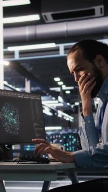 Dikey video sunucu odası bilişim uzmanı ofisteki karmaşık görevler yüzünden hayal kırıklığına uğradı. Stresli mühendis, Veri Merkezi, Kamera A 'da çalışırken sinirsel ağ yazılımı geliştiriyor.