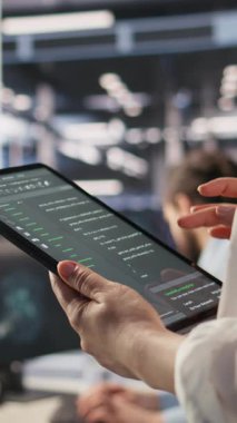 Dikey video veri merkezi sistem yöneticisinin tablet üzerindeki kodlamasını kapat, yazılım güncellemeleri yap. Aygıt ekranına bakan sunucu odası bilişim uzmanı, altyapıyı optimize ederek yapılandırmayı durdurur