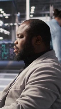 Dikey video tatmin edilmiş veri merkezi çalışanı süper bilgisayarlardaki sistem bakımını tamamlıyor. Gülümseyen teknisyen sunucuyu denetlerken yapay zeka modeli eğitim sonuçlarından memnun