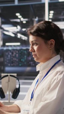 Sinir ağı yapay zeka görüntülemesini izlemek için PC kullanan dikey video veri merkezi yazılım geliştiricisi. Sunucu odasında çalışan kadın, bilgisayarla platformların öğrenme sürecini denetliyor.