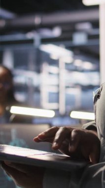 Veri merkezi mühendisinin dikey videosu AI LLM görüntülemesini izlemek için dizüstü bilgisayar kullanıyor. Sunuculara güç veren makine öğrenme süreçlerini denetlemek için dizüstü bilgisayar kullanan işçiler, kamera A