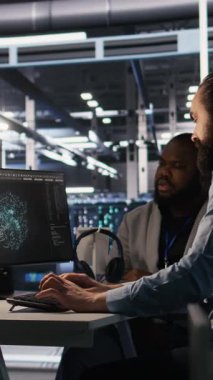 Dikey video veri merkezi mühendisi, altyapı bakımı sırasında yapay zeka otomasyon araçlarını birleştiren ekibi denetliyor. Yönetici denetimi altındaki işçiler işletim için makine öğrenme modellerini kullanır