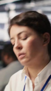 Dikey video Yorgun Veri Merkezi Mühendisi Esneme, Yapay Zeka eğitimi yapan sunucu kümeleri izleme. Yorgun sunucu çiftliği bilişim uzmanı derin öğrenmeyi yöneten bilgisayar sistemlerini denetliyor