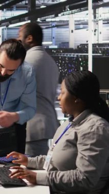 Dikey video sunucu odası yöneticisi AI eğitim verilerini yöneten çalışanlara geri bildirim sağlıyor. Ekip lideri, veri merkezindeki teknisyenle konuşuyor. Sinir sistemini destekleyen sistem operasyonlarını denetliyor.